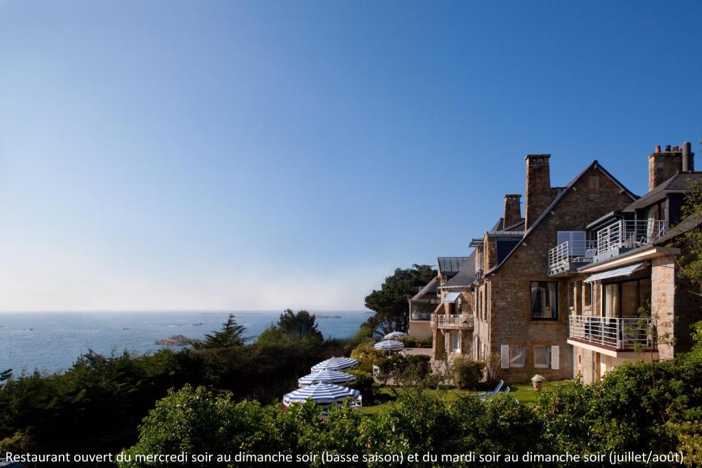 a house with umbrellas on a hill next to the ocean at Manoir de Lan Kerellec - Relais & Châteaux - Etoilé Michelin in Trébeurden