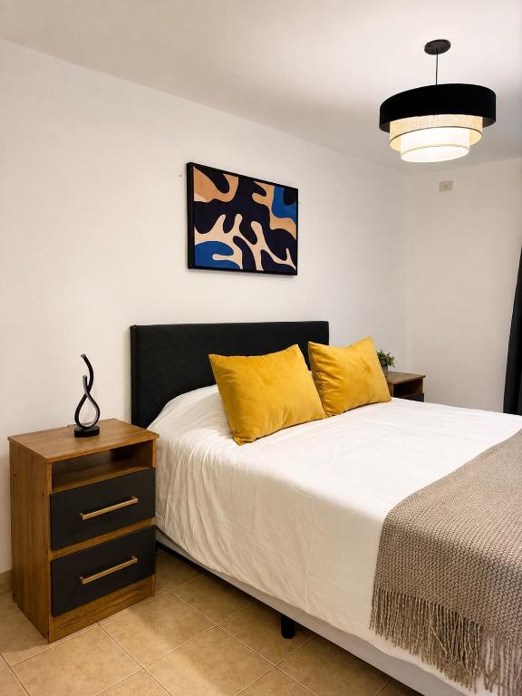 a bedroom with a bed with yellow pillows and a night stand at Paramont Rosario 4 in Rosario de la Frontera
