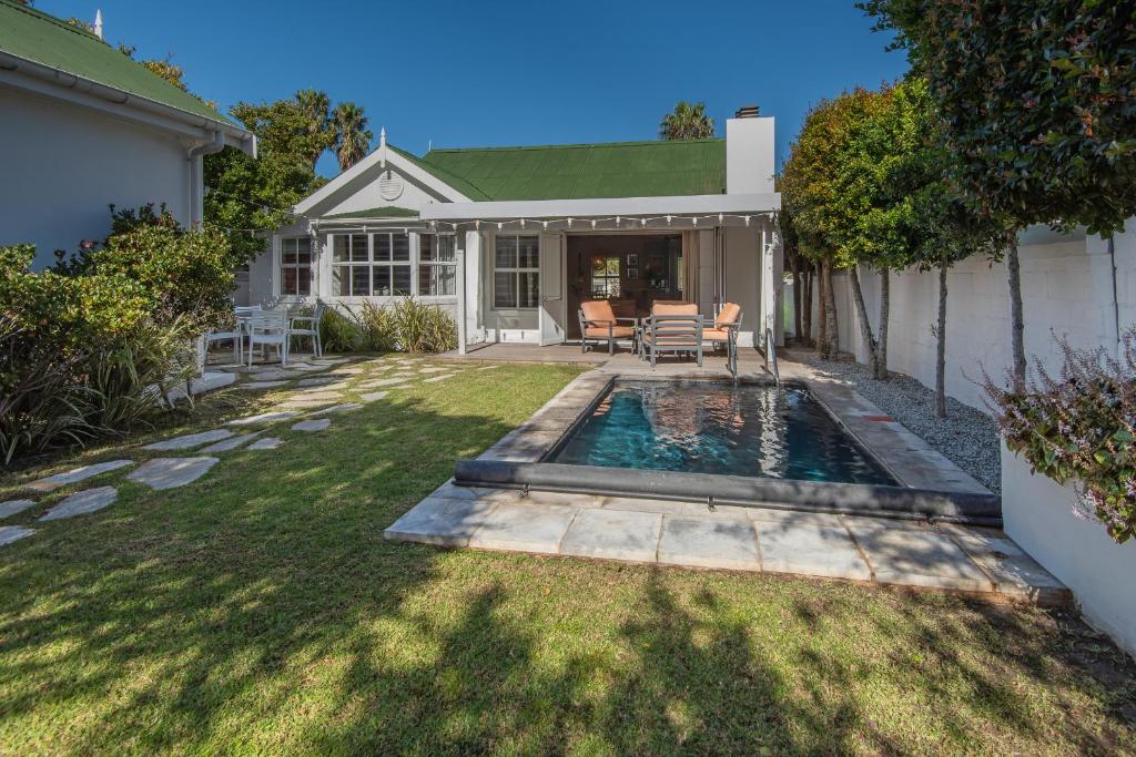 a backyard with a swimming pool and a house at Cosy Cottage Onrus - With Pool in Hermanus