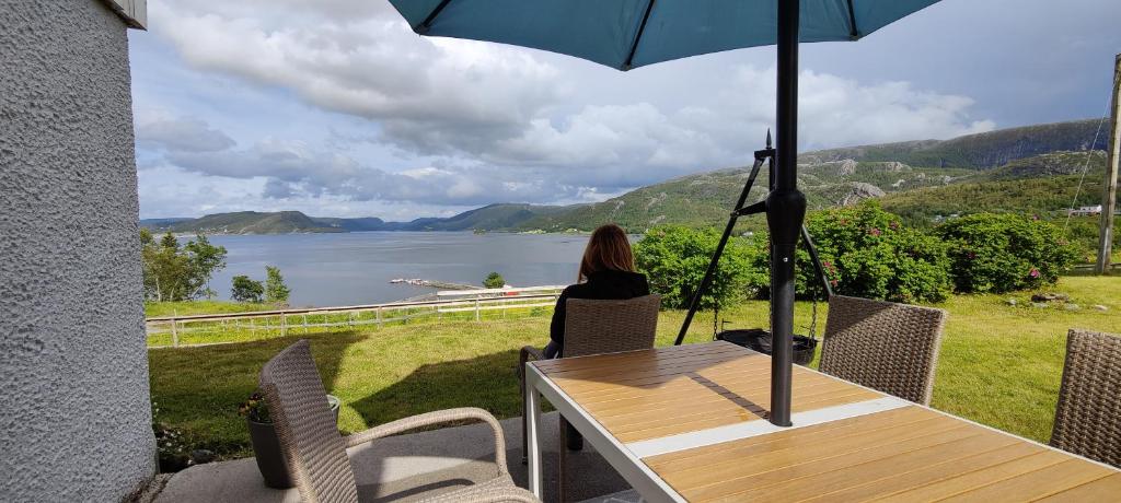 a woman sitting at a table with an umbrella at Apartment Solbakken Feriehus in Fevåg