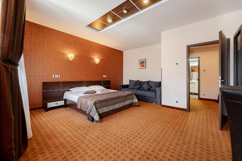 a bedroom with a bed and a couch at INTER BUSINESS Bucharest in Bucharest