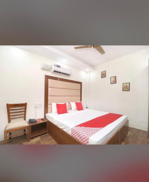 a bedroom with a bed with red pillows and a chair at FB Hotel in Kharar