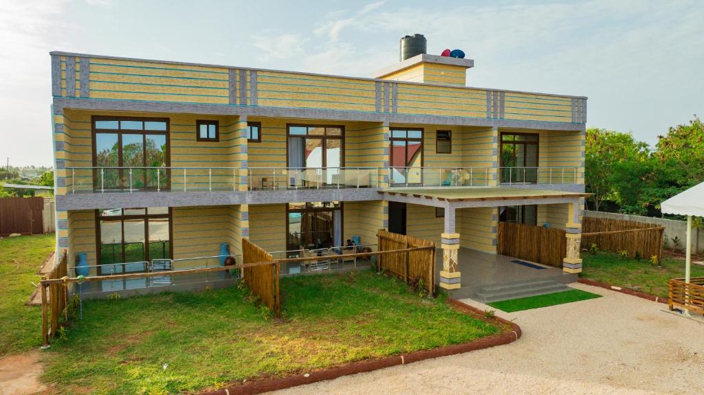 a large yellow house on top of a field at Tulivu Resort in Kituoni