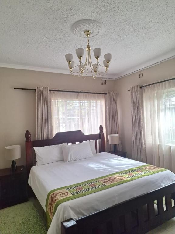 a bedroom with a large bed with a chandelier at Eastview Guest House in Harare