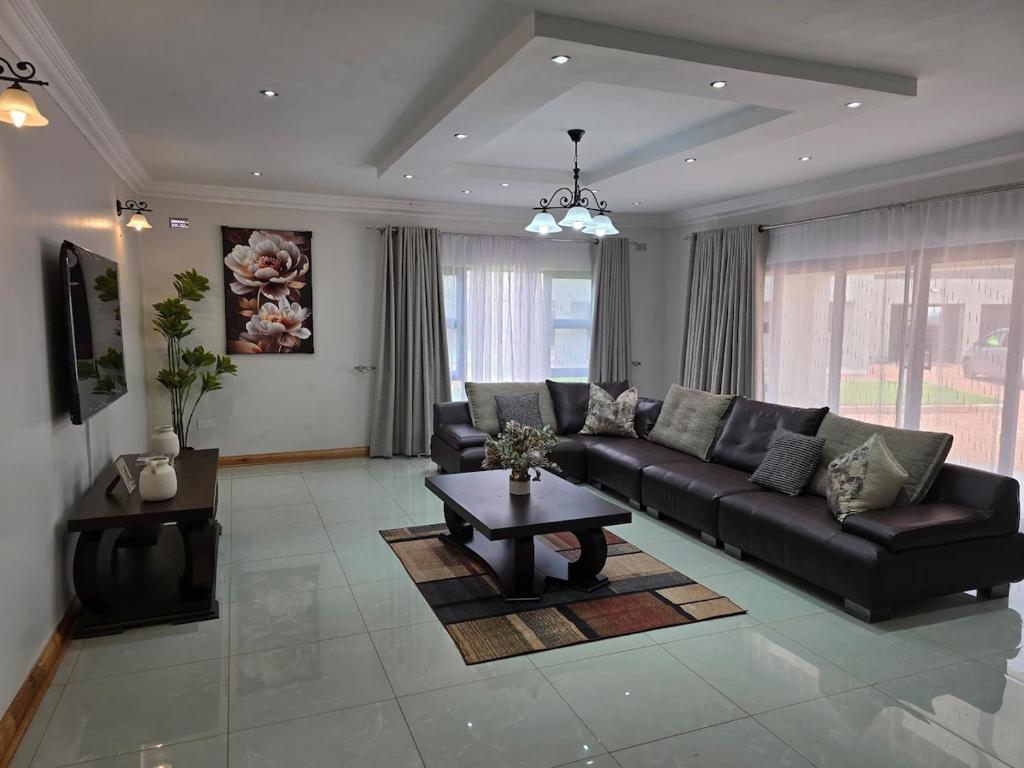 a living room with a black couch and a table at Ivory & Mane Estate - Jacaranda in Harare