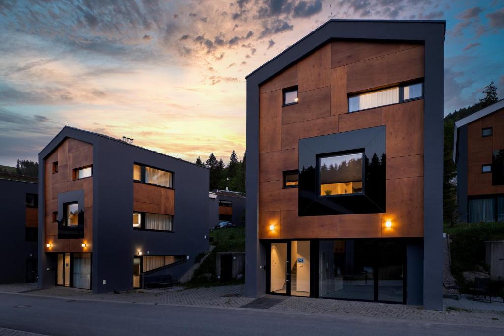 a two story building with a sunset in the background at Chalet Pod Brdom - Apartments in Ružomberok