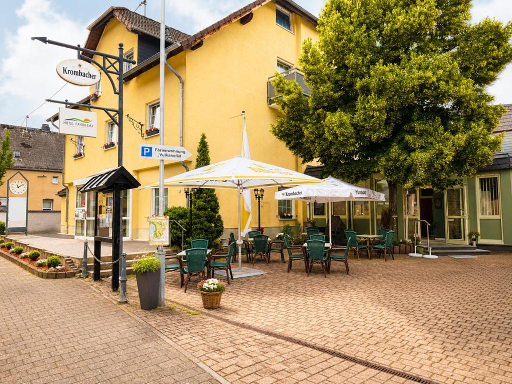 a patio with chairs and umbrellas in front of a building at Hotel Panorama Nickenich in Nickenich