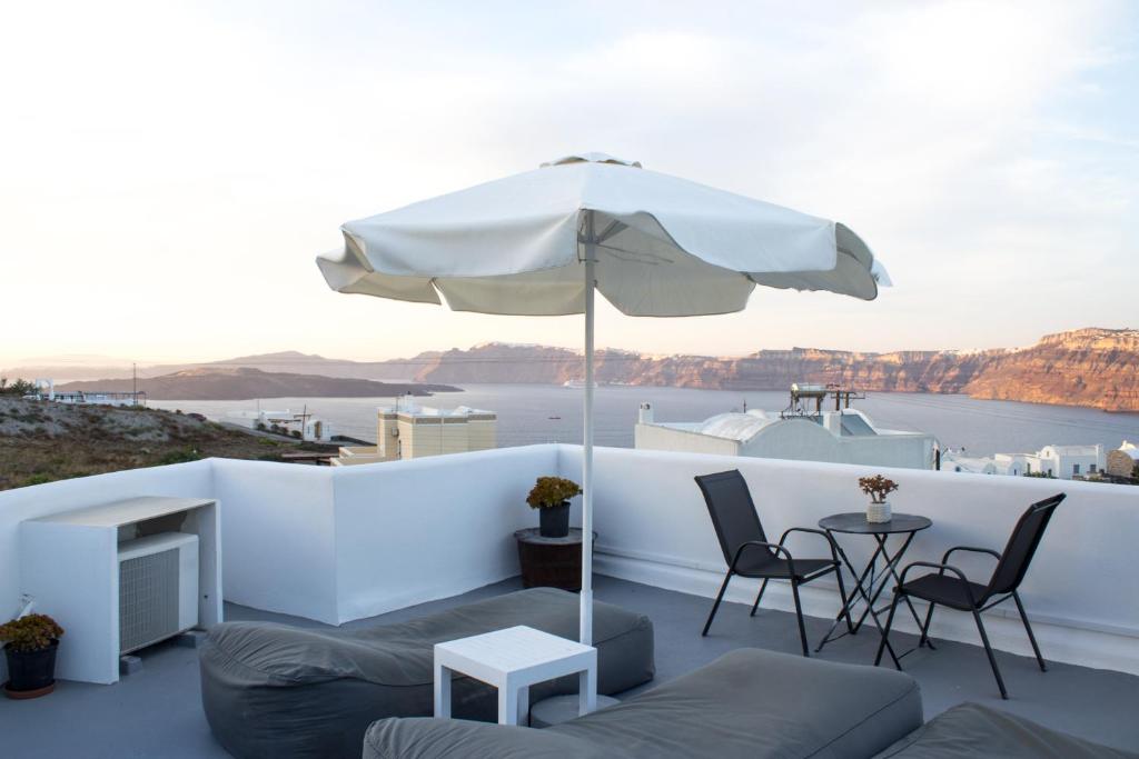 a patio with an umbrella and a table and chairs at Villa Solasta #2 with jacuzzi in Santorini in Akrotiri