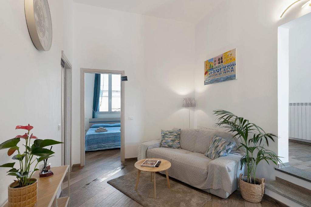 a living room with a couch and two potted plants at Il Leone Bianco Affittacamere in Albenga
