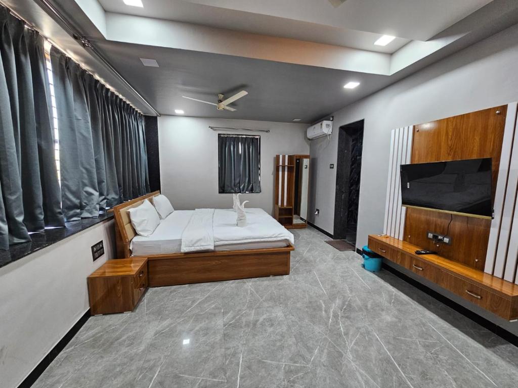a bedroom with a bed and a flat screen tv at Hotel Pooja Inn Pandharpur in Pandharpur