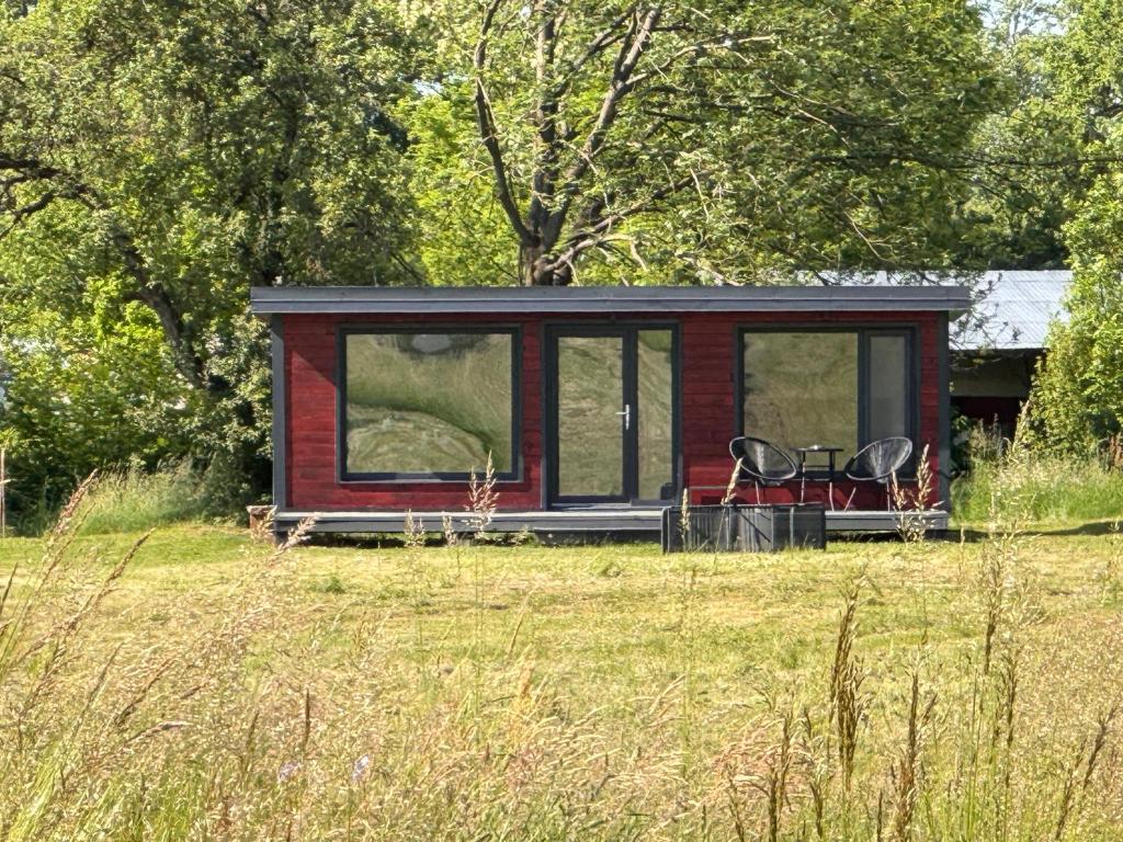 eine rot-schwarze Hütte mit zwei Stühlen auf einem Feld in der Unterkunft Tiny House ROA in Recea