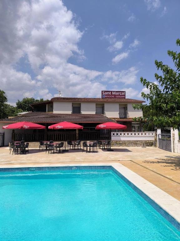 a hotel with a pool and tables and umbrellas at Hostal Restaurant Sant Marçal in Amer