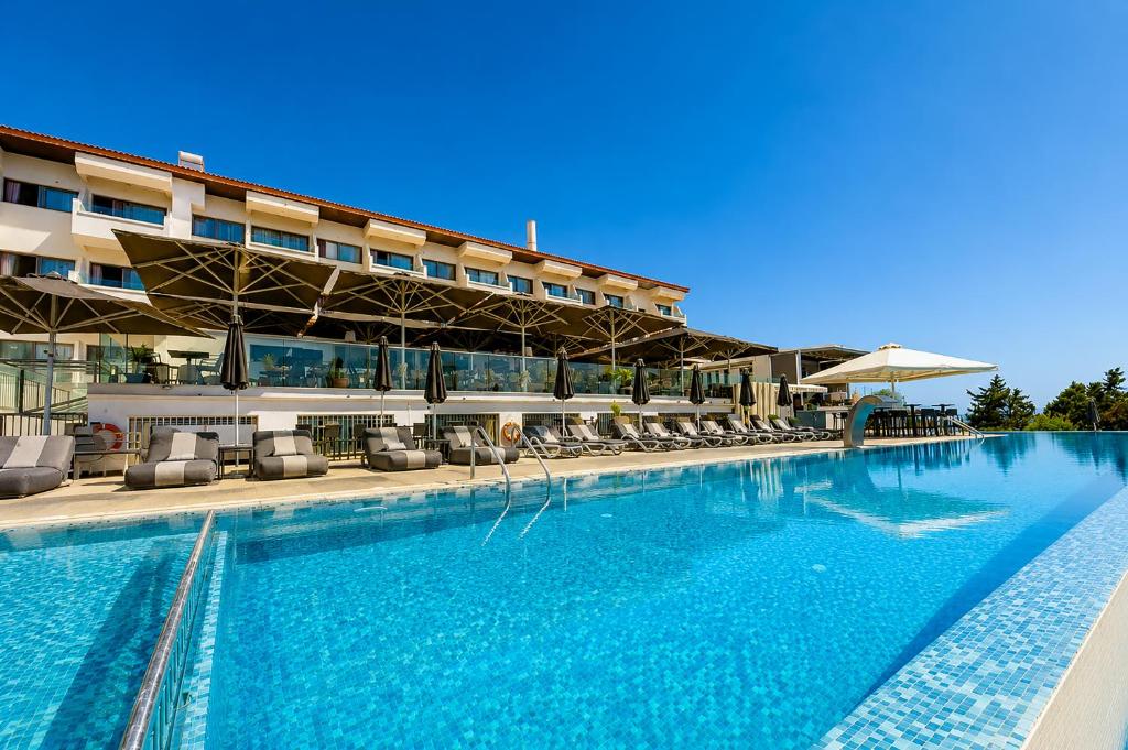 a swimming pool with chairs and a hotel at Droushia Heights Hotel in Drousha