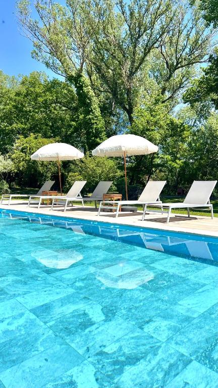 a group of chairs and umbrellas in a swimming pool at Le Moulin de Montségur in Montségur-sur-Lauzon