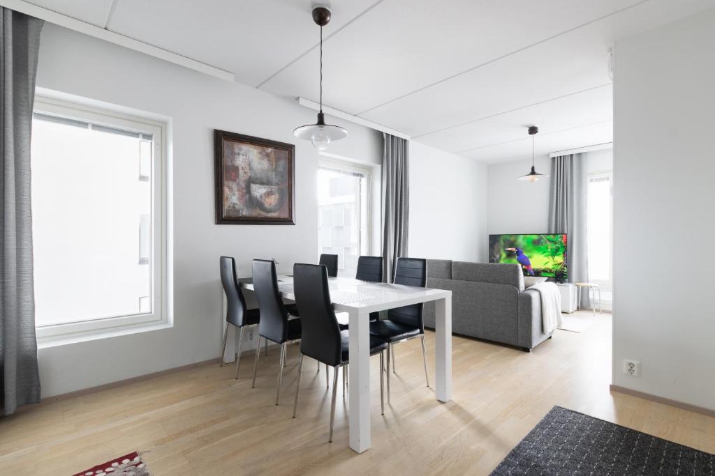 a dining room with a white table and black chairs at Moderni avara yksiö Jyväskylän ydinkeskustassa in Jyväskylä