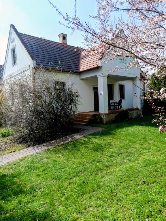 a white house with a grass yard at Park Vendégház in Herend