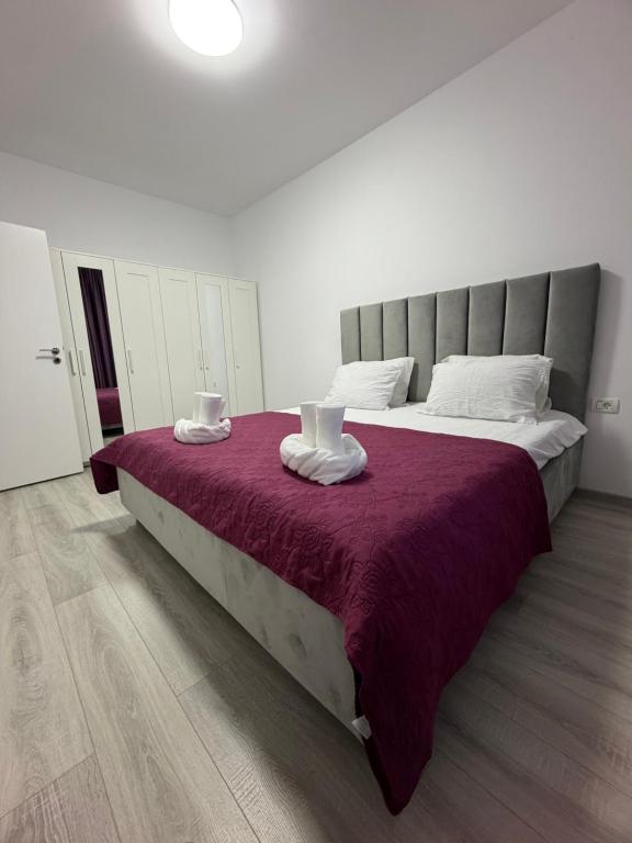 a bedroom with a large bed with a purple blanket at C&A Apartment in Giroc