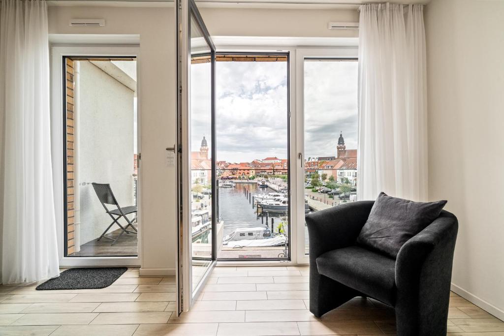 a living room with a chair and a large window at Möwe - Apartment in der Hafenresidenz mit Balkon & Wellness in Waren