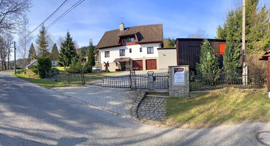 a house with a fence in front of a street at Penzion Mühl in Bedřichov