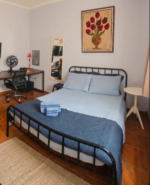 a bedroom with a bed with a blue comforter at Quarto Aconchegante com Wi-Fi self check-in e garagem in Pouso Alegre