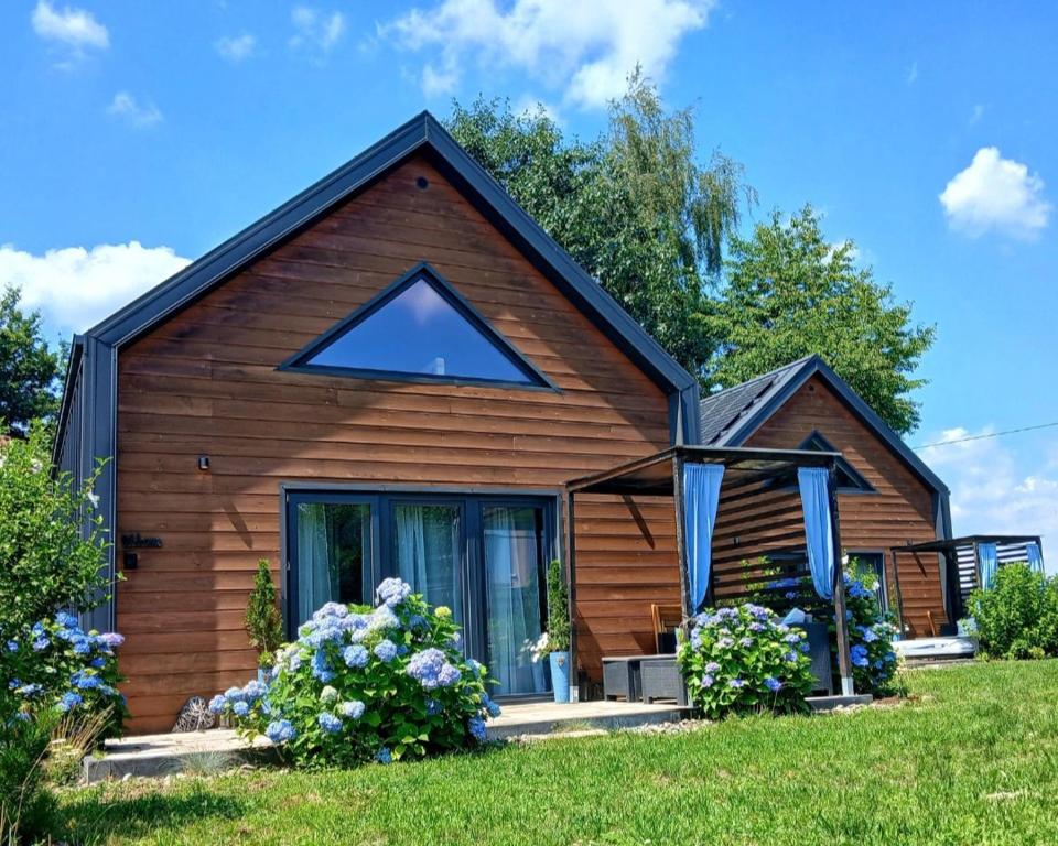 a small wooden house with flowers in the yard at Eleonor Accommodation exclusive house in Liszki