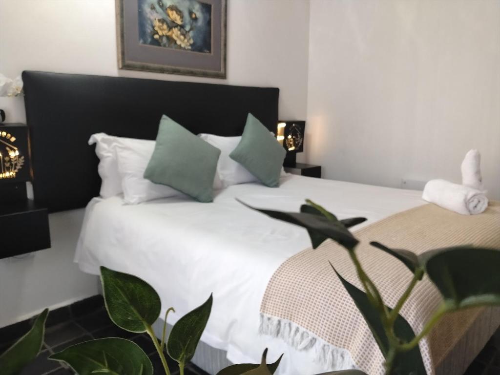a bedroom with a bed with white sheets and green pillows at Nylstroom Guesthouse in Modimolle