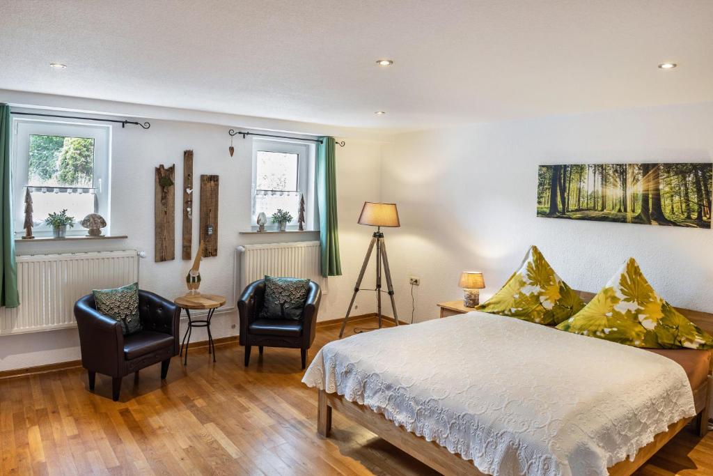 a bedroom with a bed and two chairs at Ferienwohnung An der Wublitz in Leest