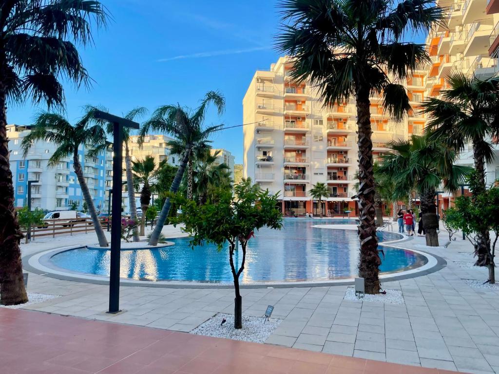 a swimming pool with palm trees and buildings at SunSis Apartment in Shëngjin