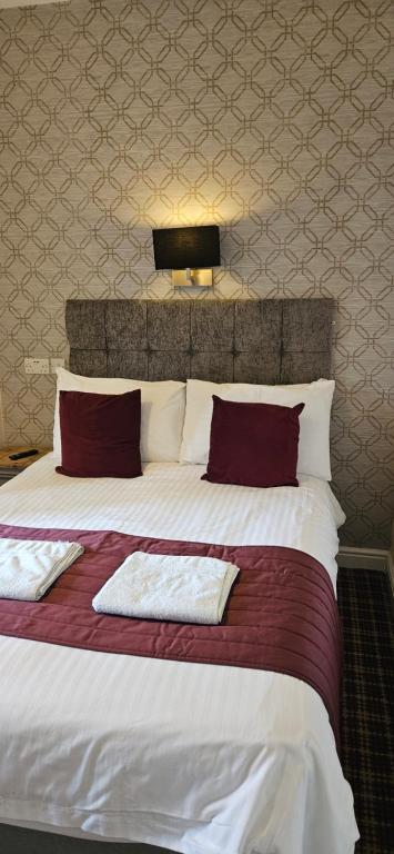 a bedroom with a large bed with red and white pillows at The Trafford Hotel in Blackpool