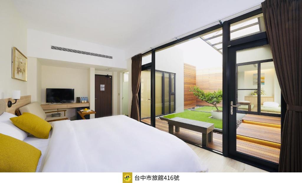 a bedroom with a large white bed and a balcony at Hotel Z in Taichung