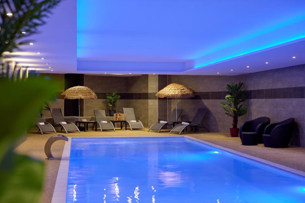 a swimming pool in a hotel with chairs and tables at Zenitude Swiss Apparthotels in Ferney-Voltaire