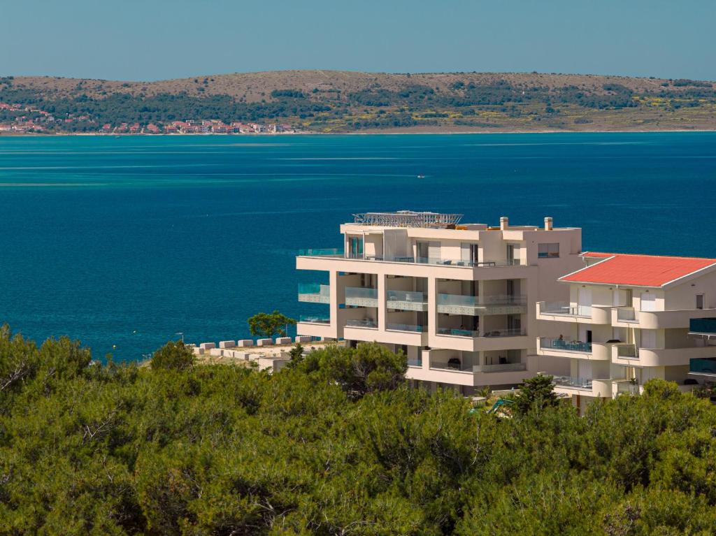 a building on top of a hill next to the water at Smile Apartments in Povljana