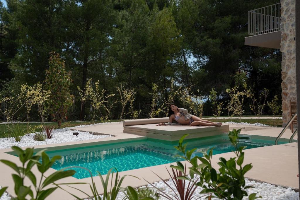 a woman in a bikini laying next to a swimming pool at Domus Gaia Suites in Nikiti