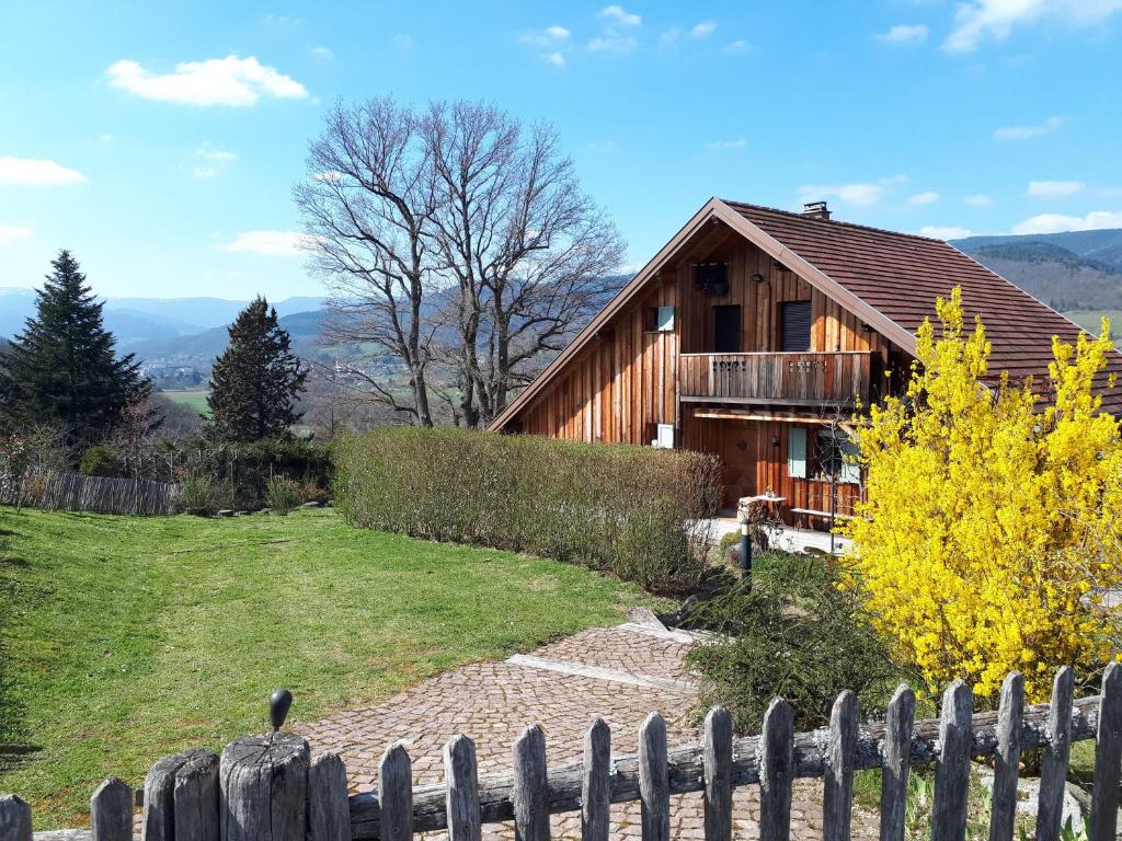 a wooden house with a fence in front of it at Le chalet du Chardonneret in Soultzbach-les-Bains