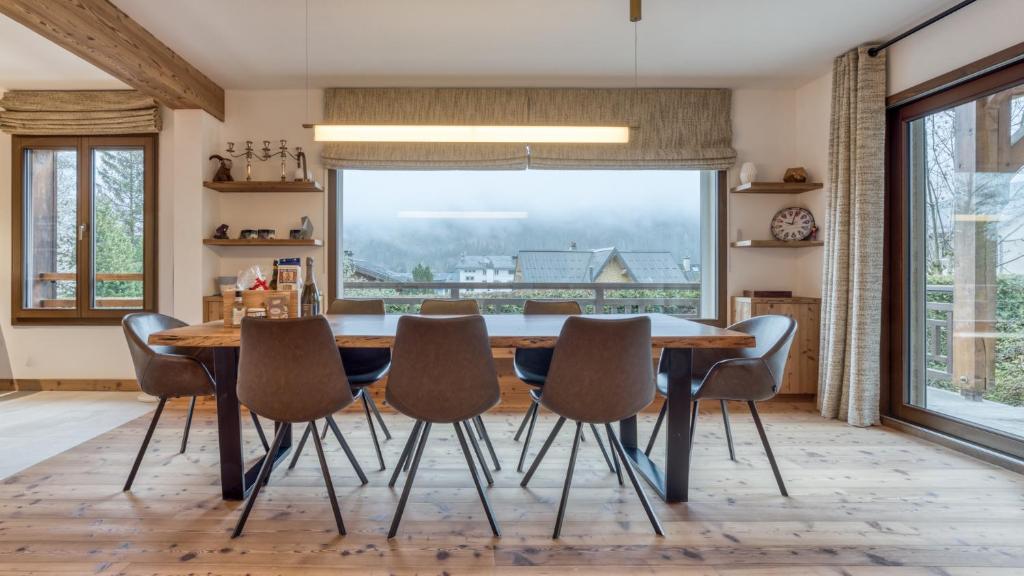 a dining room with a table and chairs and a large window at Chalet Le Savoy in Chamonix