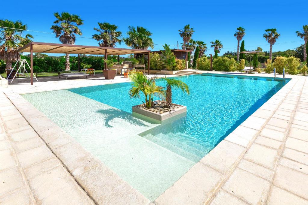 a swimming pool with palm trees in the middle at Agriturismo Li Frutti in Otranto
