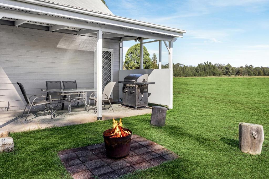 a patio with a grill and a table in a field at Madigan Cottages - The Barn Pet Friendly in Lovedale