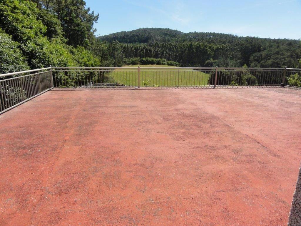 a large red concrete patio with a fence and trees at Casa Emiliano in Cee