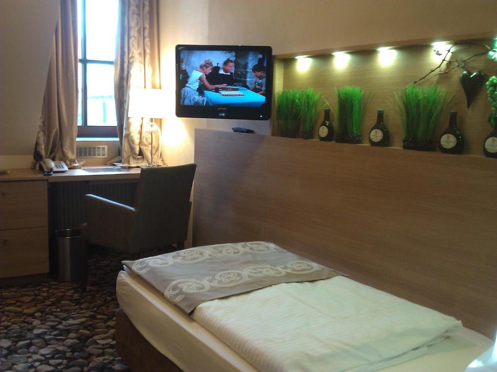 ファイツヘーヒハイムにあるシュプントロッホ - ダス ホテル＆ヴァインレストランのベッド1台、壁掛けテレビが備わるホテルルームです。
