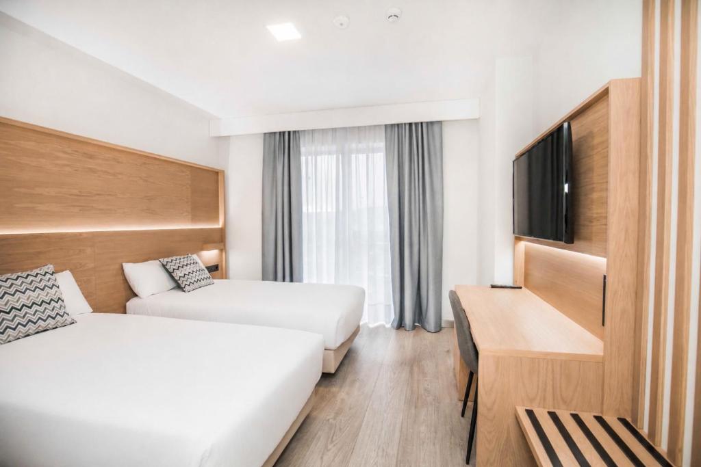 a hotel room with two beds and a flat screen tv at Hotel Ciudad De Ávila in Ávila
