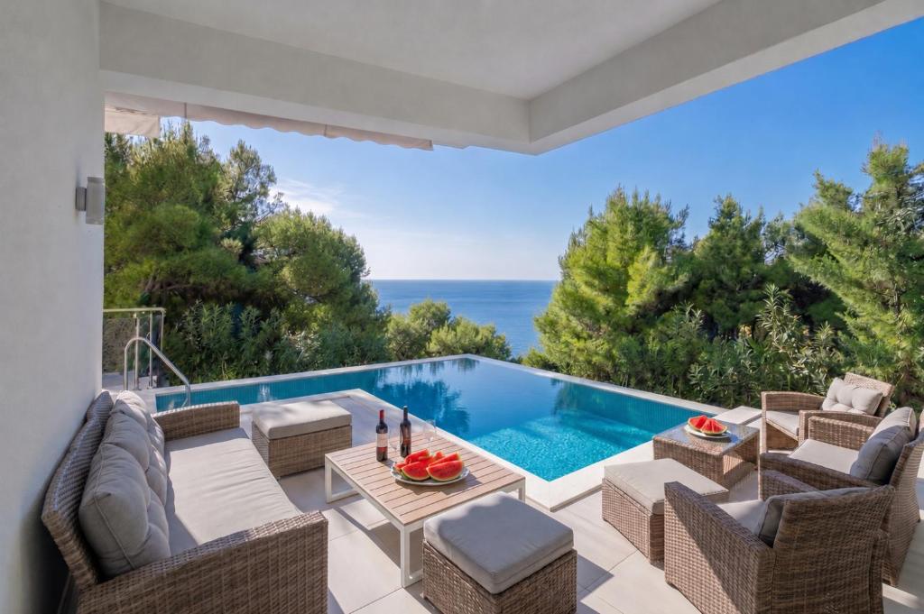 a patio with a pool and chairs and a table at Villa Berfami - Managed by Excelsior Villas in Podstrana
