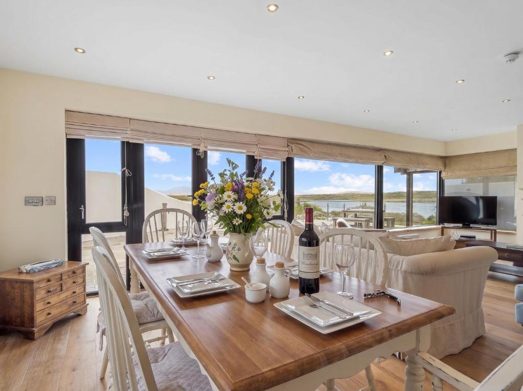 a dining room with a table with flowers and wine bottles at Calla Lookout in Roundstone