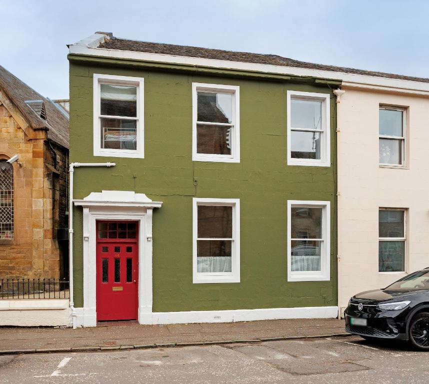 a green house with a red door on a street at The Greenhouse Ayr in Ayr