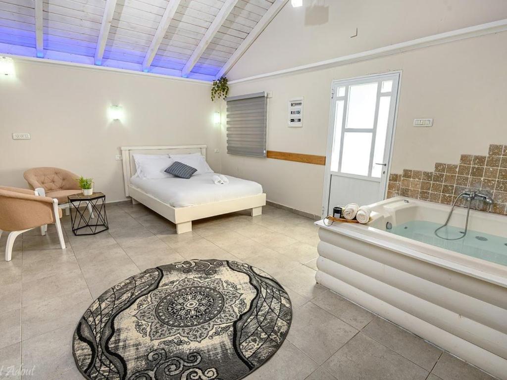 a bedroom with a bed and a bath tub and a bedzinski at בקתות לוטן דלתון - 4 בקתות עם ג'קוזי פרטי ו-2 בריכות משותפות in Shahar
