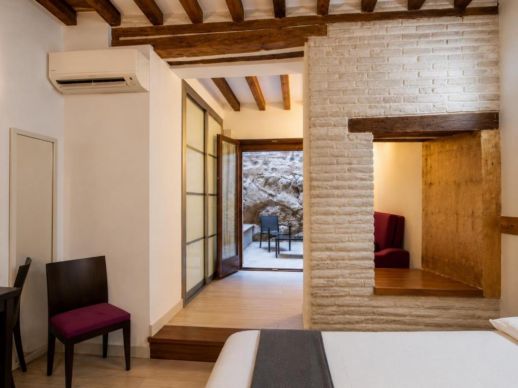a bedroom with a bed and a brick wall at Capricho Toledano, Apartamento con terraza en el centro histórico in Toledo