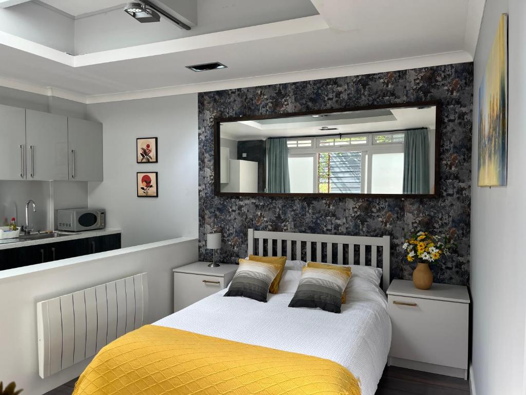 a bedroom with a bed and a mirror on the wall at The Welcome Haven - Cozy Studio with Patio & Free Parking in Chislehurst