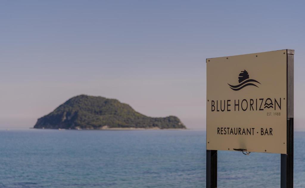 a sign in front of the ocean with an island in the background at Blue Horizon Studios in Laganas