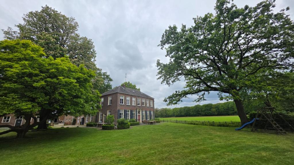 a large house with a large yard with a playground at Hotel Restaurant Roerdinkhof in Winterswijk