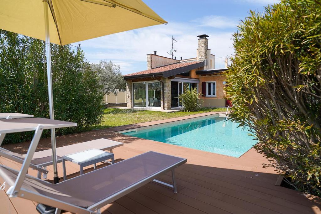 a patio with an umbrella and a swimming pool at Villa Ulivi Private Pool & Lake View in Montinelle