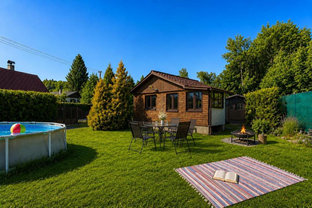 a backyard with a table and chairs and a house at Modrobílá chatka u rybníka in Holoubkov